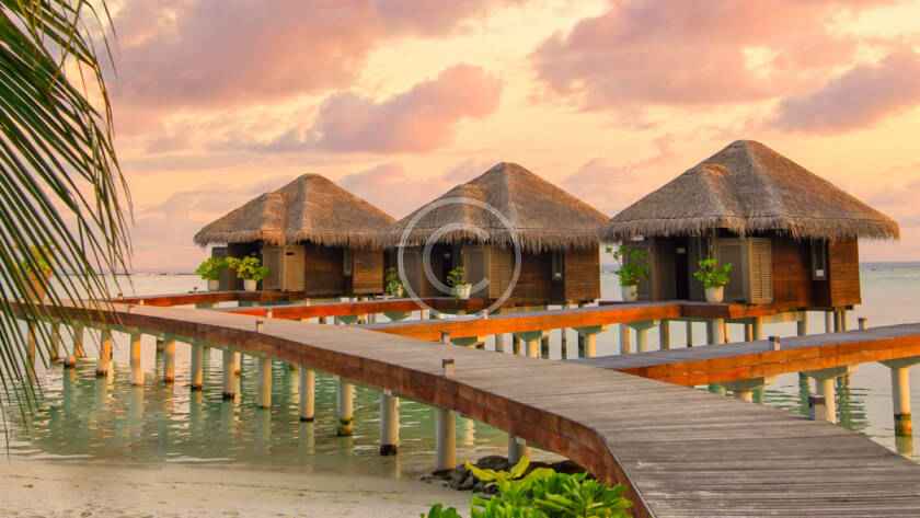 A boardwalk leads to the water 's edge at sunset.