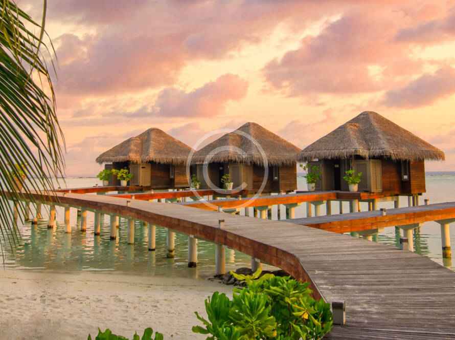 A boardwalk leads to the water 's edge at sunset.