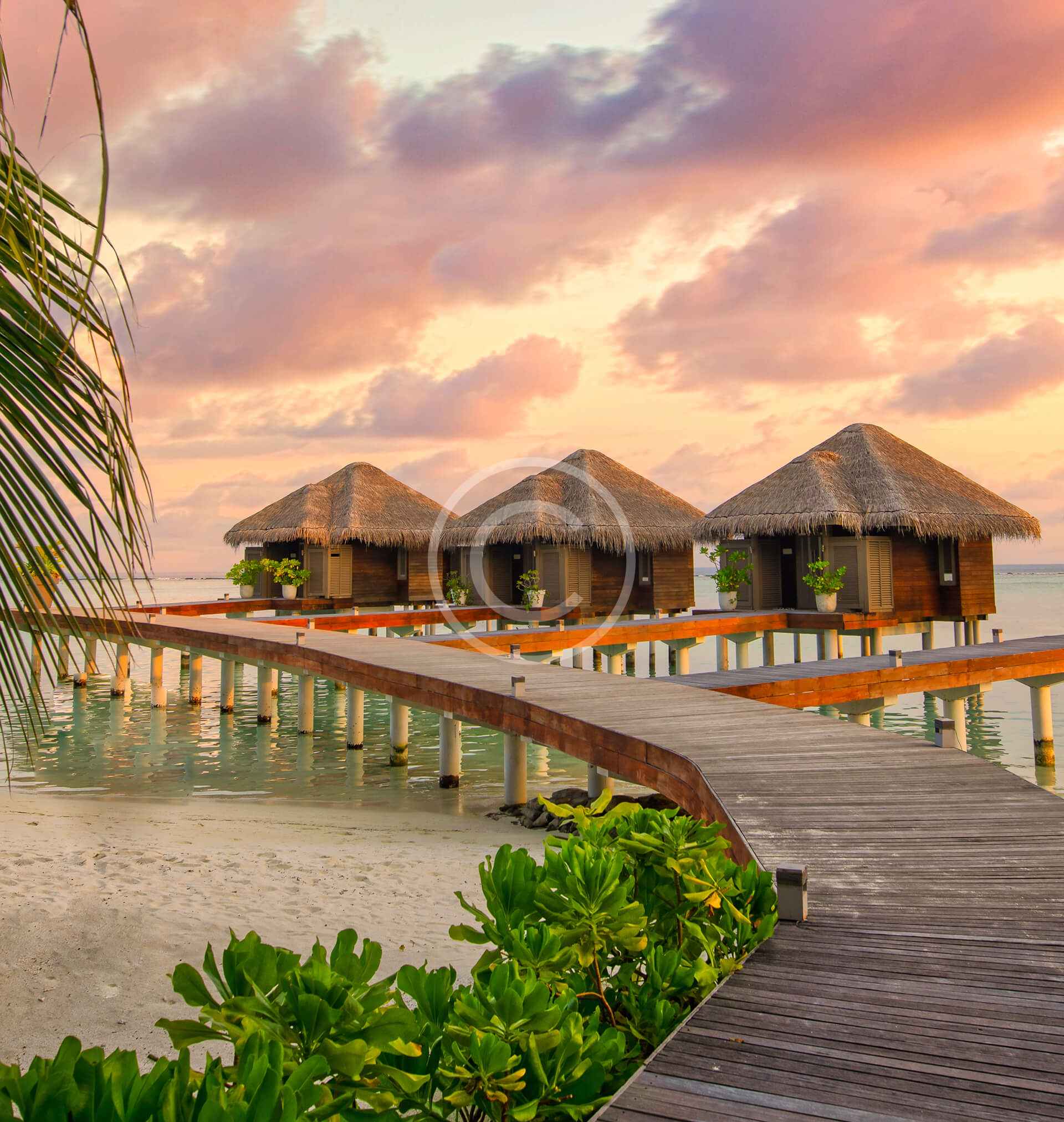 A boardwalk leads to the water 's edge at sunset.
