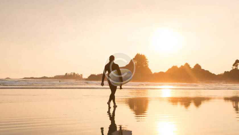 A man walking on the beach with his surfboard.