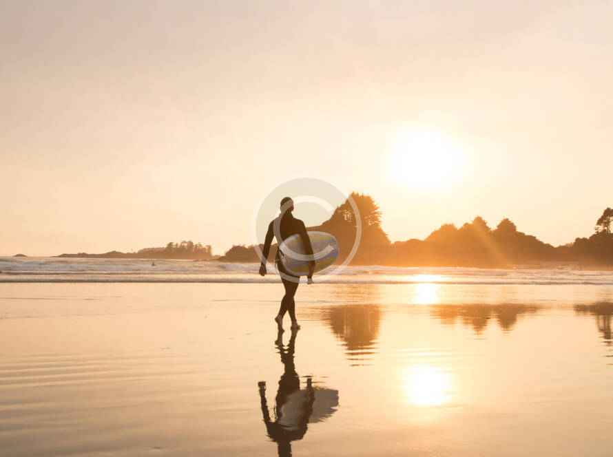A man walking on the beach with his surfboard.