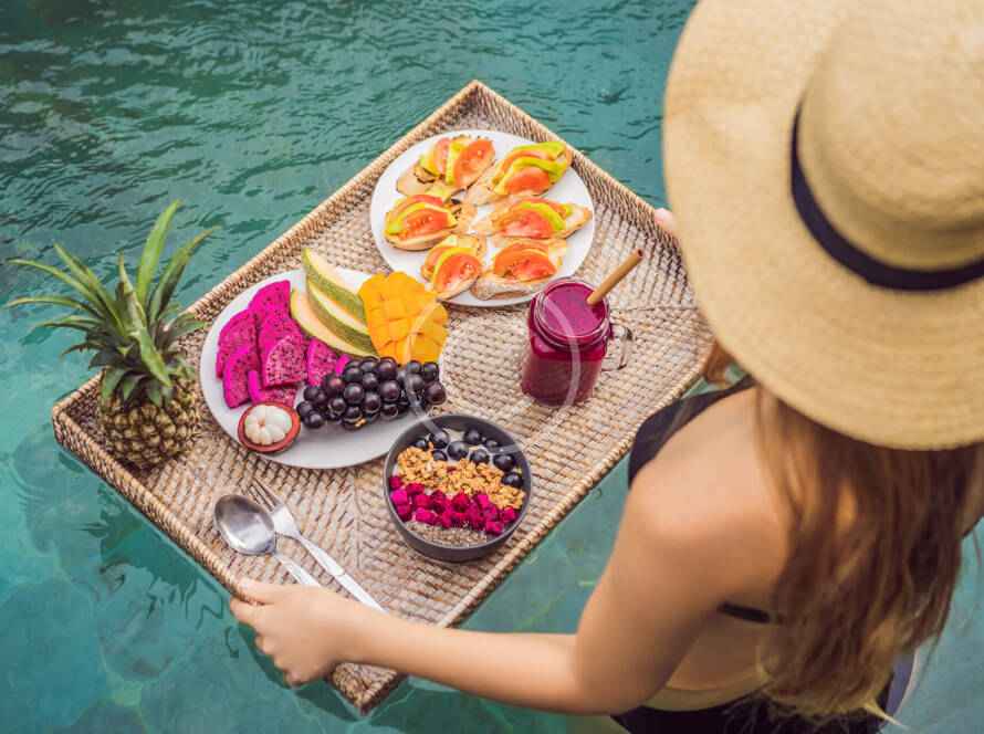 A woman in a hat and sunglasses holding a tray of food.