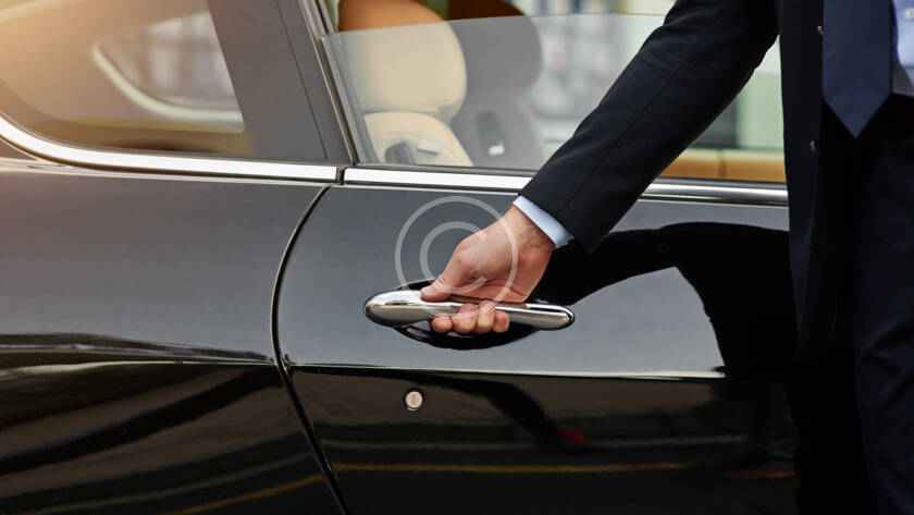 A person is holding the door handle of a car.
