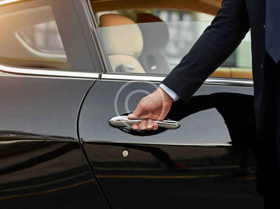 A person is holding the door handle of a car.