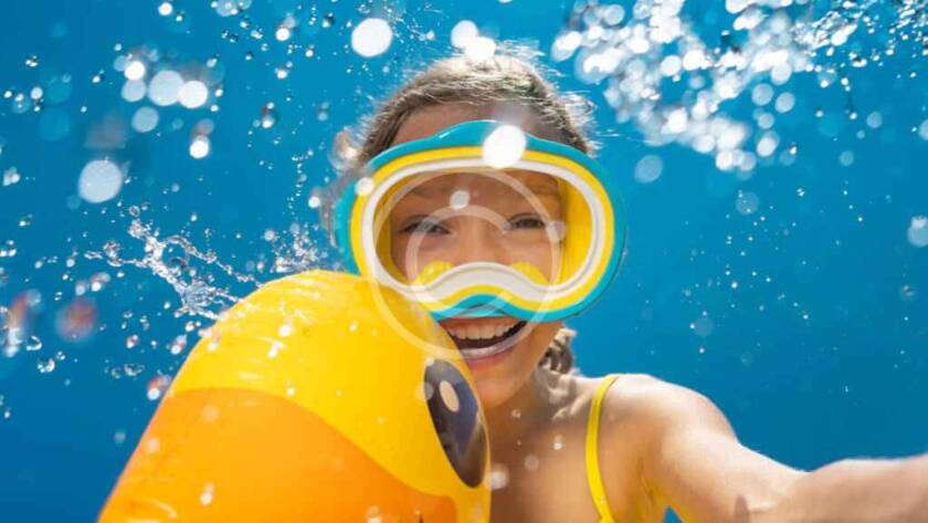 Smiling girl underwater with inflatable duck.