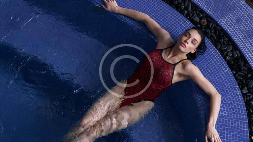 Woman relaxing in a blue tiled pool.