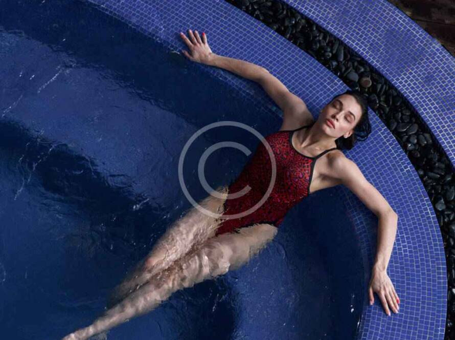 Woman relaxing in a blue tiled pool.