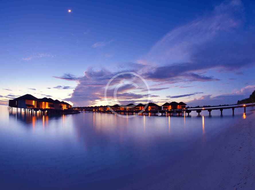 A view of the water at dusk with lights on.