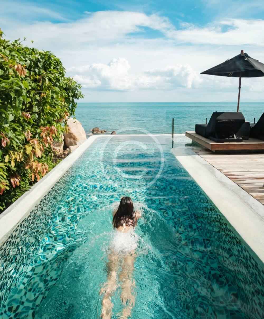 A woman swimming in the pool of an ocean front home.