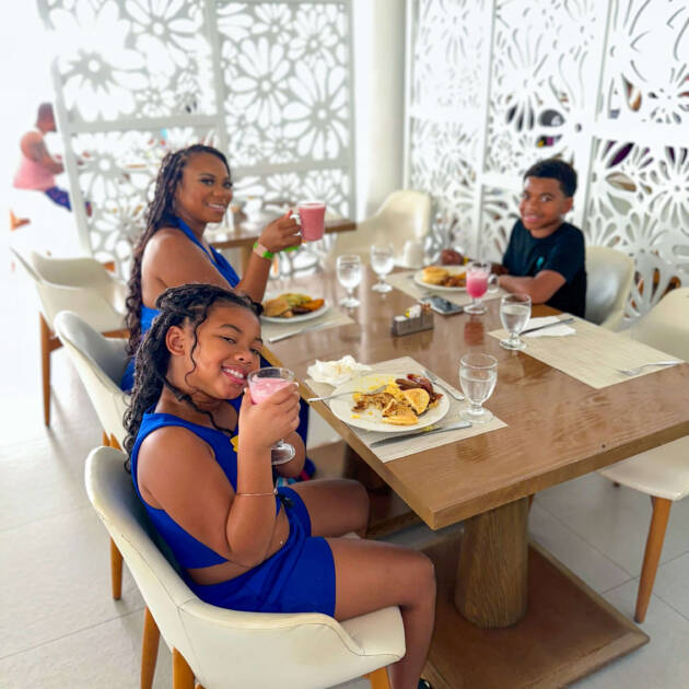 Three people sitting at a table eating food.