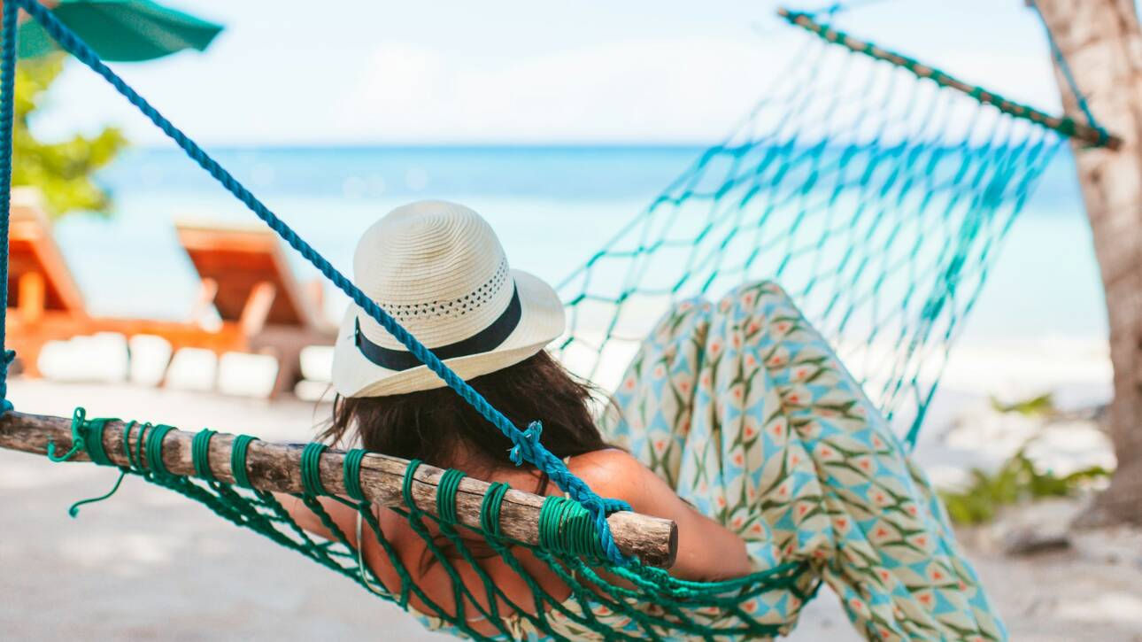 Adorable girl on tropical vacation relaxing in hammock