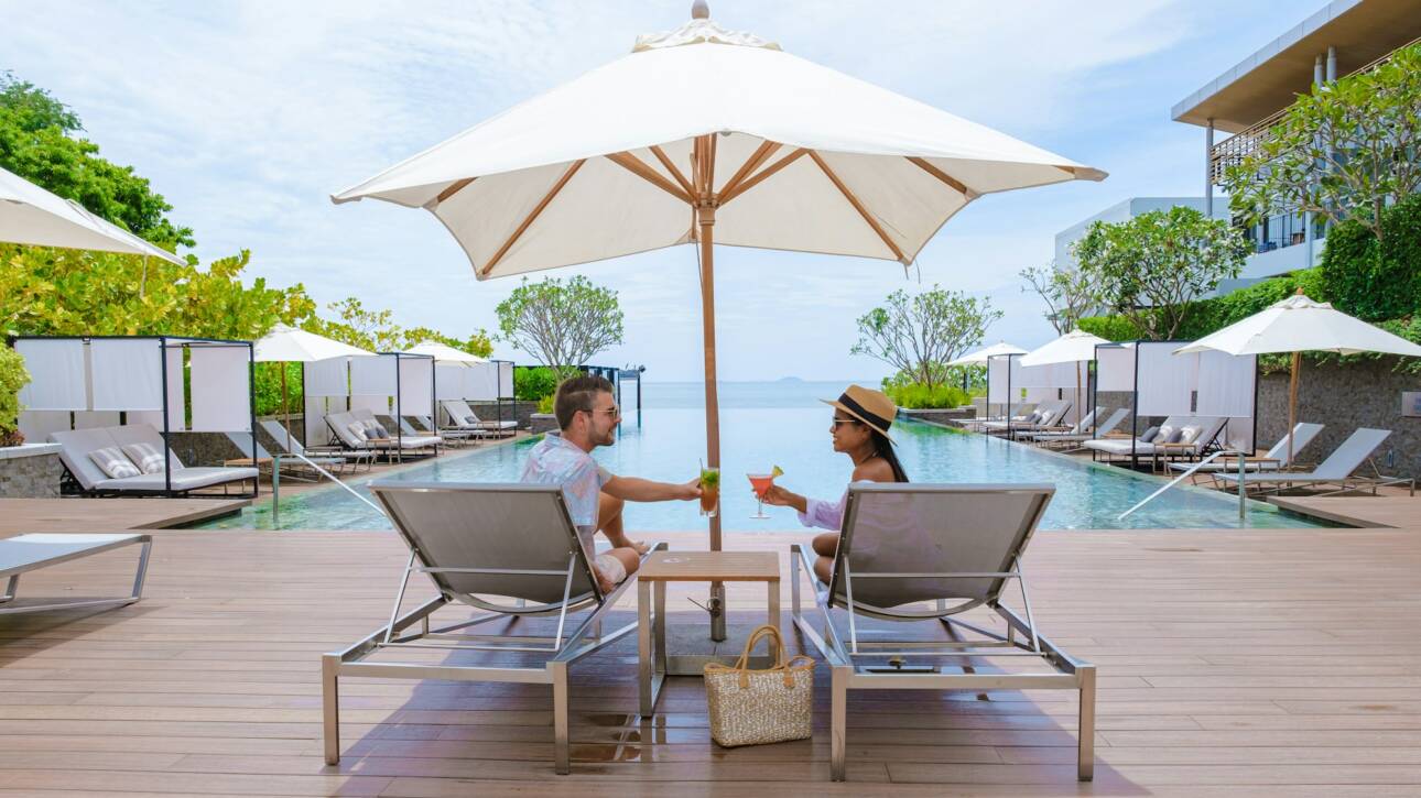 couple men and women relaxing on a beach chair in fron of the swimming pool at a luxury vacation