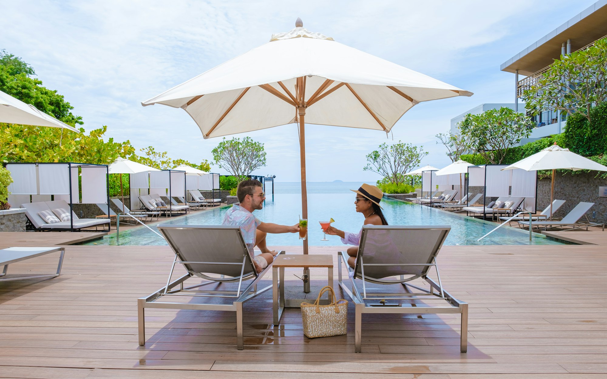 couple men and women relaxing on a beach chair in fron of the swimming pool at a luxury vacation