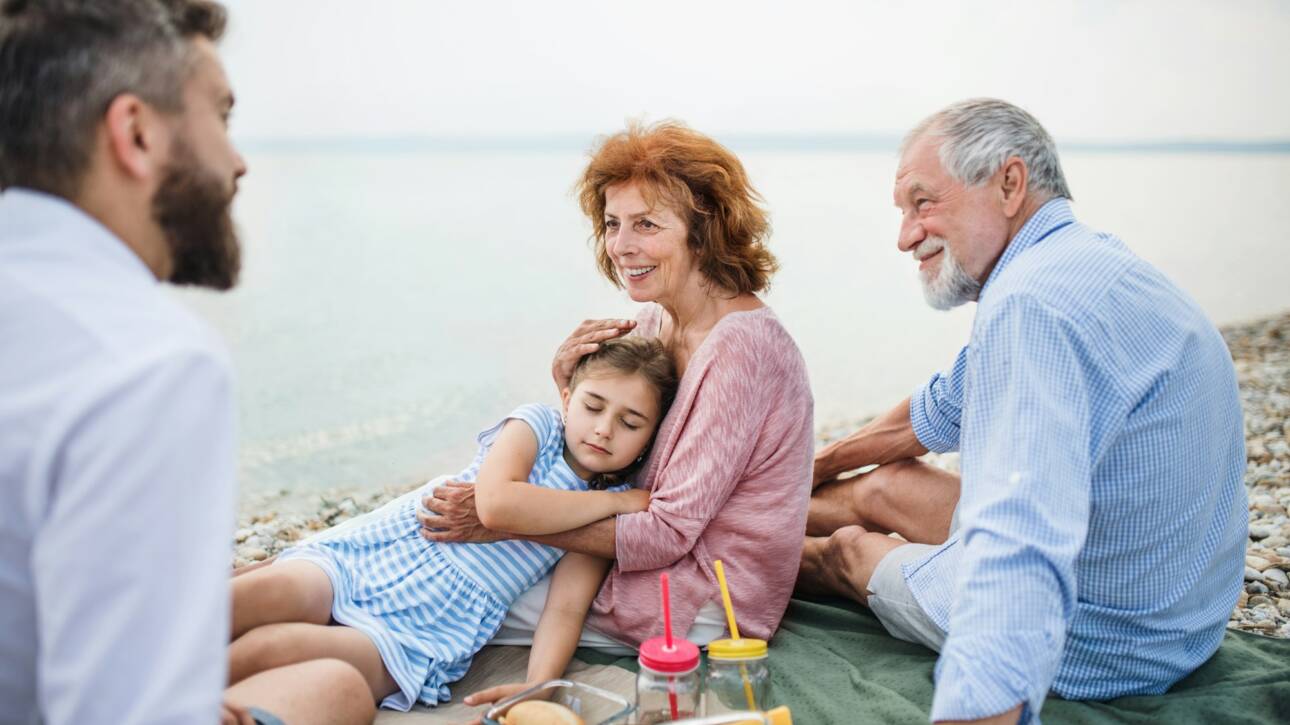 Multigeneration family on a holiday by the lake, having picnic