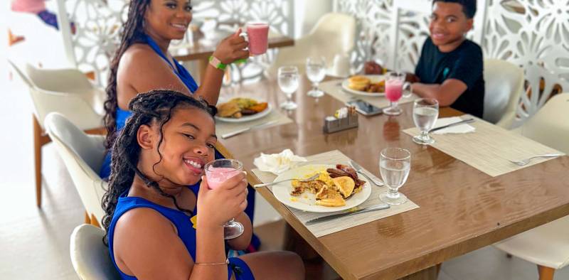 Three people sitting at a table eating food.