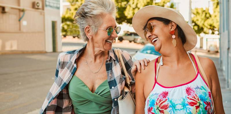 Happy, senior women and laugh in city for walking, travel and bonding on vacation and urban backgro